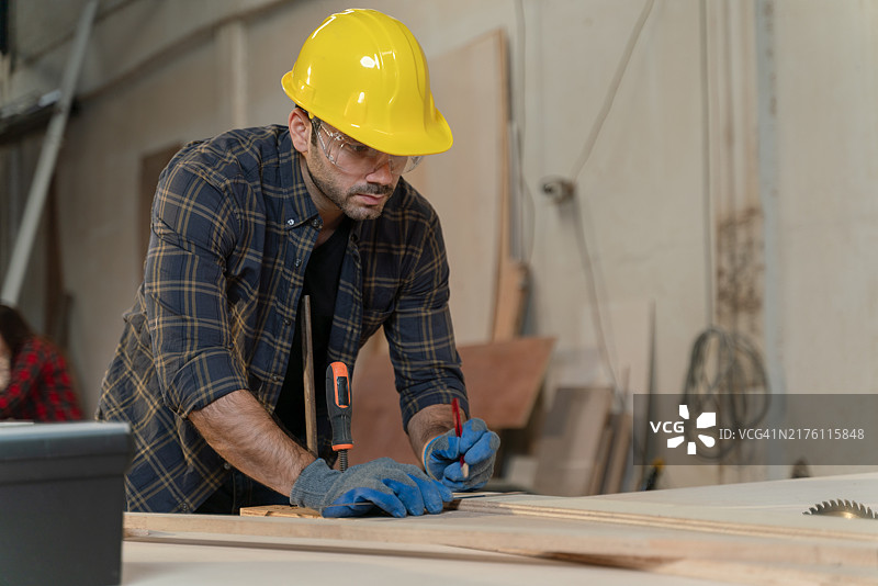 戴黄色安全帽的男士在木头上写字图片素材