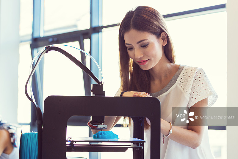 年轻的亚洲女人使用3D打印机图片素材