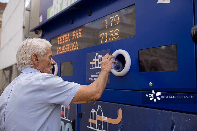 年长的男人在机器中回收塑料瓶图片素材