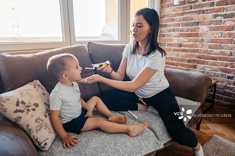 中年妇女给儿子喂止咳药图片素材