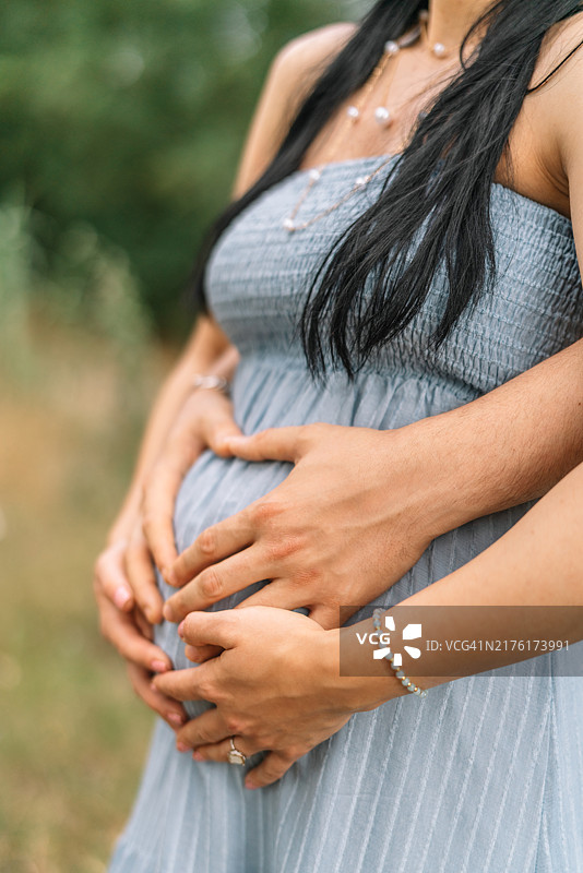 孕妇在户外抚摸腹部的腰部特写图片素材