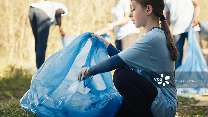 疲惫的小女孩从森林里捡垃圾和塑料瓶图片素材