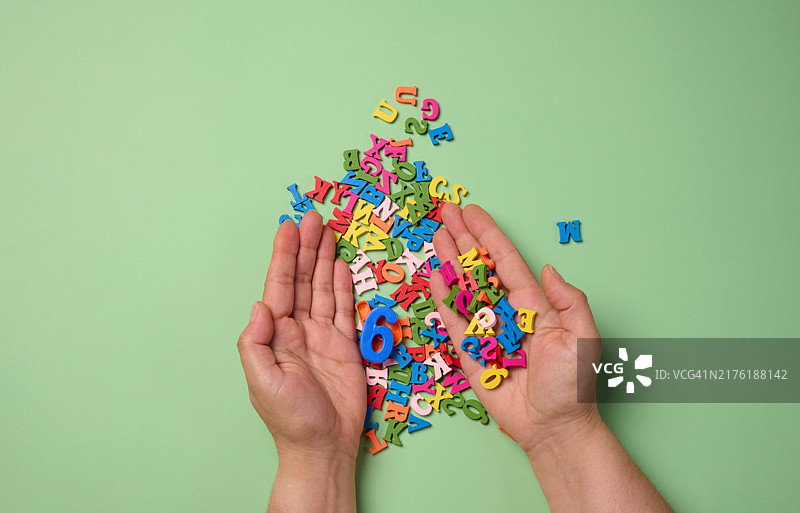绿色背景上的女人手和散落的英文字母图片素材