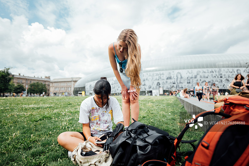 年轻女背包客在公园休息，看手机图片素材