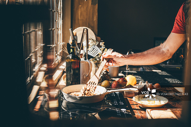 男子在平底锅中煮切片蘑菇。图片素材