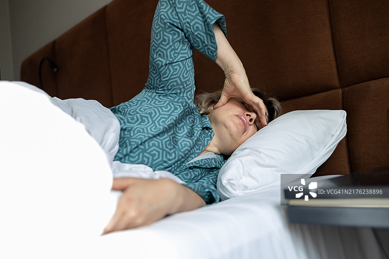 悲伤的女人躺在床上头痛图片素材