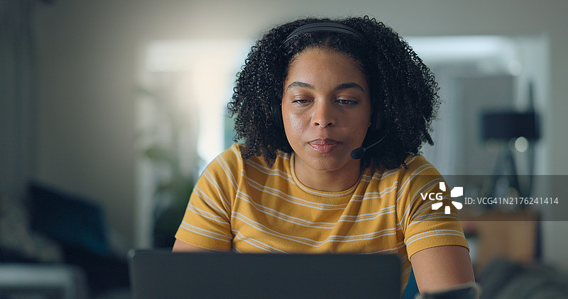 穿着休闲服装的年轻漂亮女人，在室内工作时使用笔记本电脑并微笑。图片素材