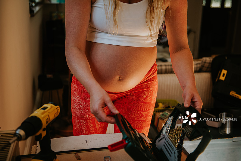 年轻孕妇使用电动工具进行DIY图片素材