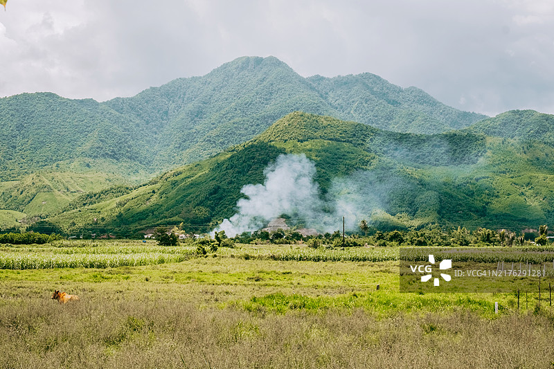 宁静的绿色山脉风景，山谷中烟雾缭绕，天空多云图片素材
