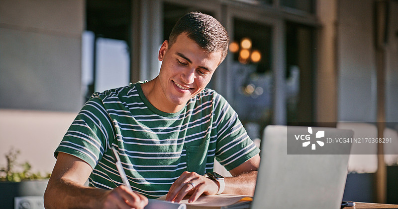 大学生在校园里使用笔记本电脑或在笔记本上写作图片素材