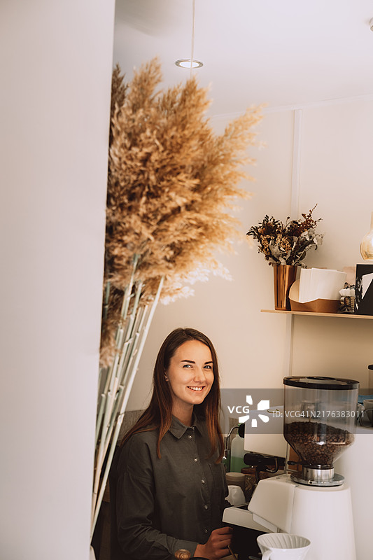 年轻女咖啡师在咖啡店吧台后制作咖啡图片素材