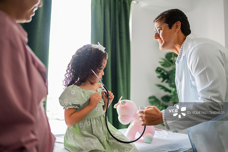 在医院咨询期间与医生交谈并使用听诊器的女童图片素材