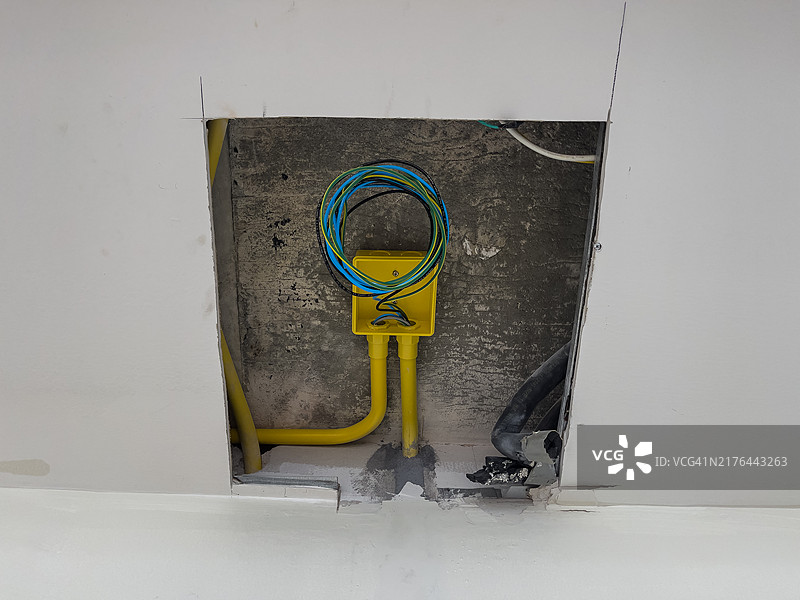 墙壁的裸露部分显示了电线和黄色导管，在建造或维修工作期间有一个小的切口图片素材