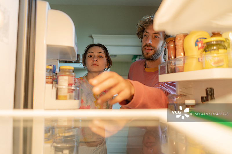 一起做饭并在冰箱里寻找食材的男女图片素材