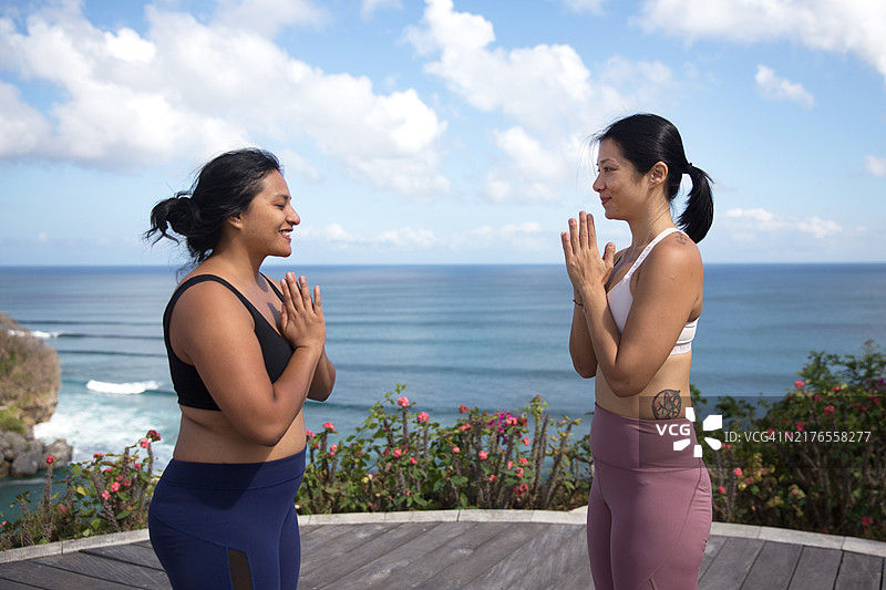 两位瑜伽朋友在海边屋顶露台度假村互相问候图片素材