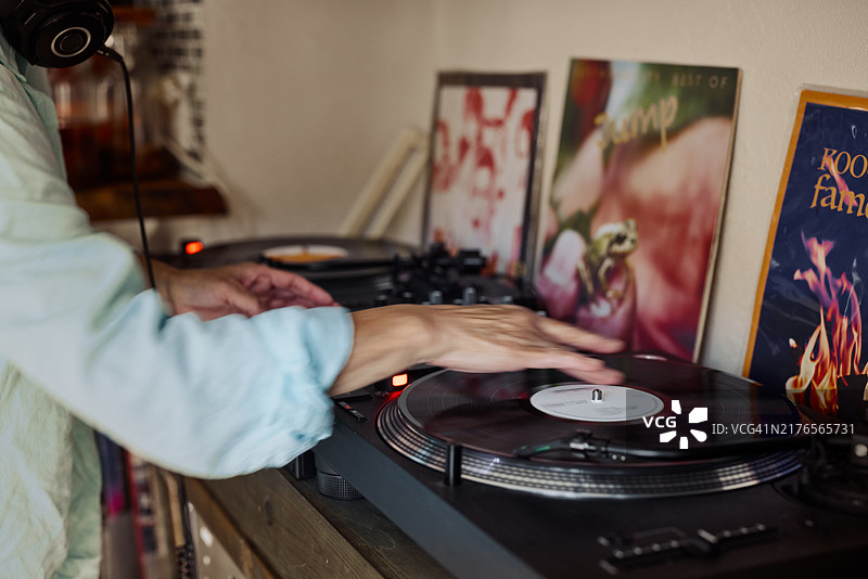 老年妇女的手在DJ转盘上播放怀旧音乐的模拟唱片特写图片素材