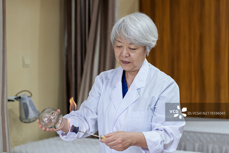 资深女中医为患者进行拔罐疗法图片素材