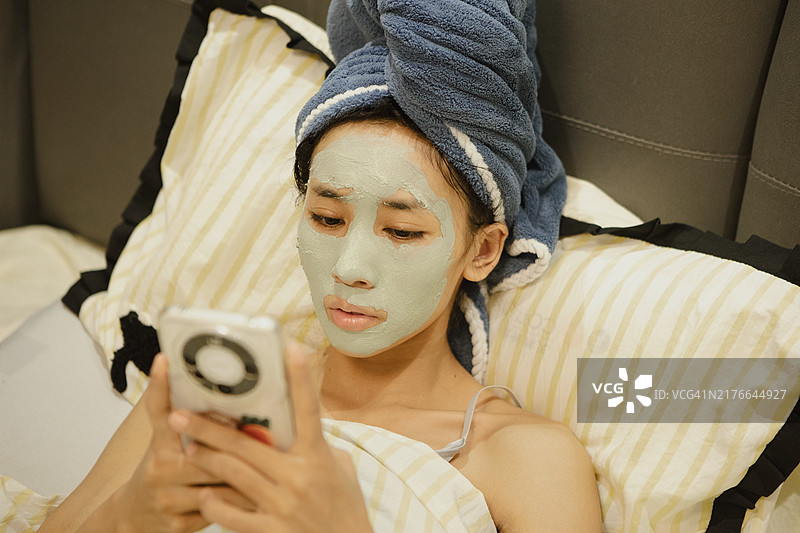 在家里的床上涂抹泥膜的女人图片素材