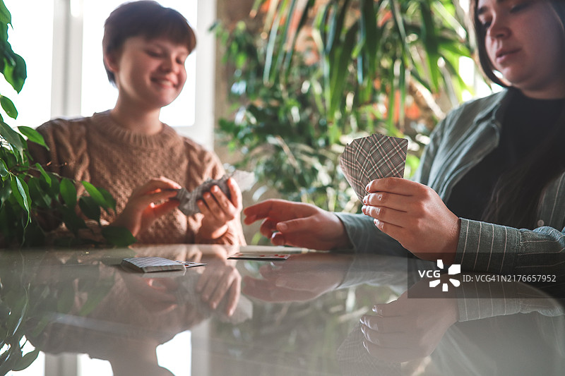 舒适夜晚，大码女士与少女桌边玩牌图片素材