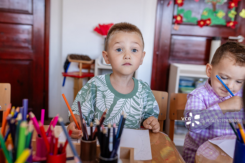 在充满活力的教室里绘画的，穿着图案上衣的男孩图片素材