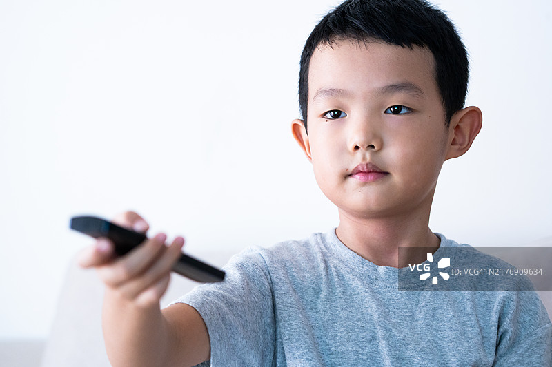 儿童手持遥控器看电视图片素材