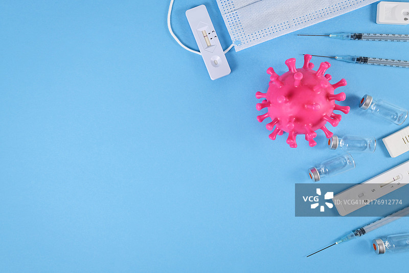 抗击冠状病毒疫情的工具：快速抗原检测、医用口罩、疫苗瓶和注射器，蓝色背景带复制空间图片素材