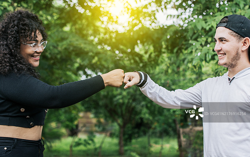 户外击拳的两位年轻少女，象征友谊的朋友击拳图片素材