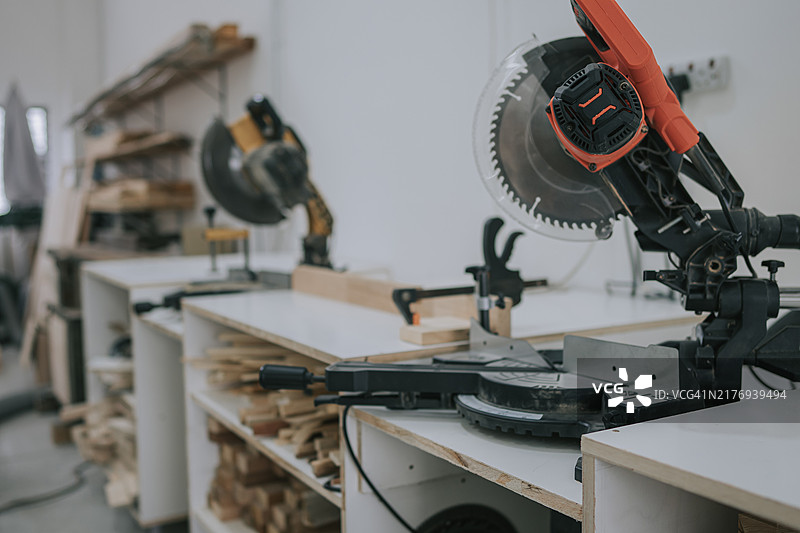 家庭作坊中的电动圆锯和木屑，木工车间堆放着切割好的木板图片素材