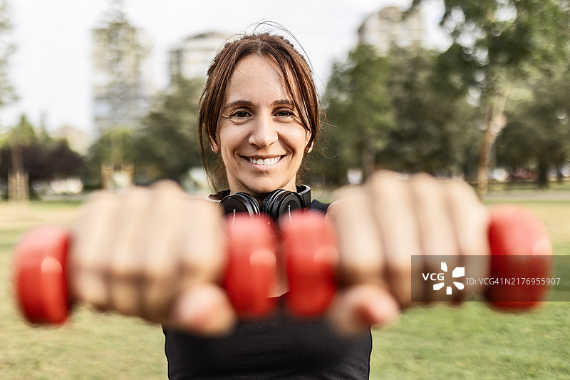 专注的女人在公园里举哑铃图片素材