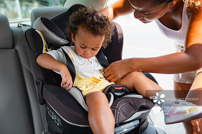 儿童对着正在系安全带的母亲咧嘴笑图片素材