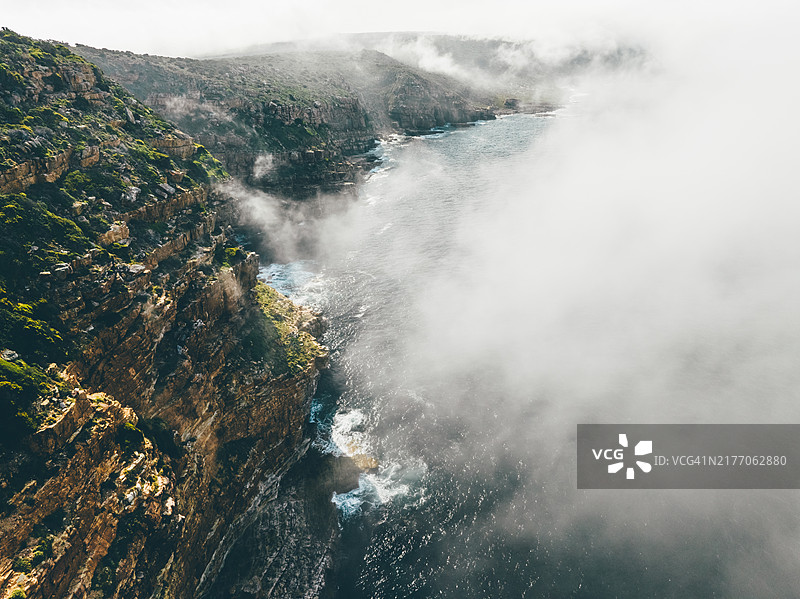 雾气弥漫的海洋与岩石海岸线的鸟瞰图。图片素材