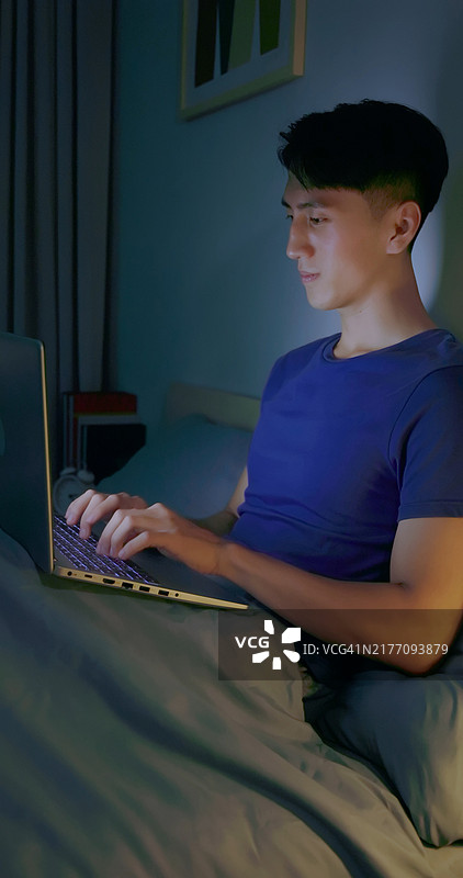 男人在床上使用笔记本电脑图片素材