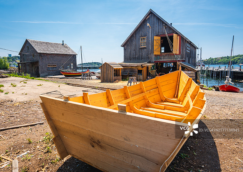 等待油漆和润色的木制单桅船停靠在船屋旁图片素材