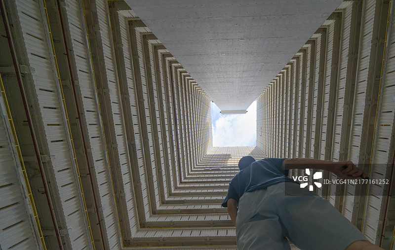 一个男人站在方形屋檐下，探索出口的可能性，表达困境和出路的概念图片素材