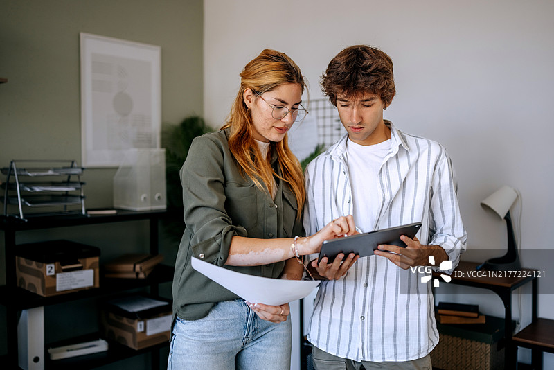 两位年轻同事在现代办公室使用平板电脑图片素材