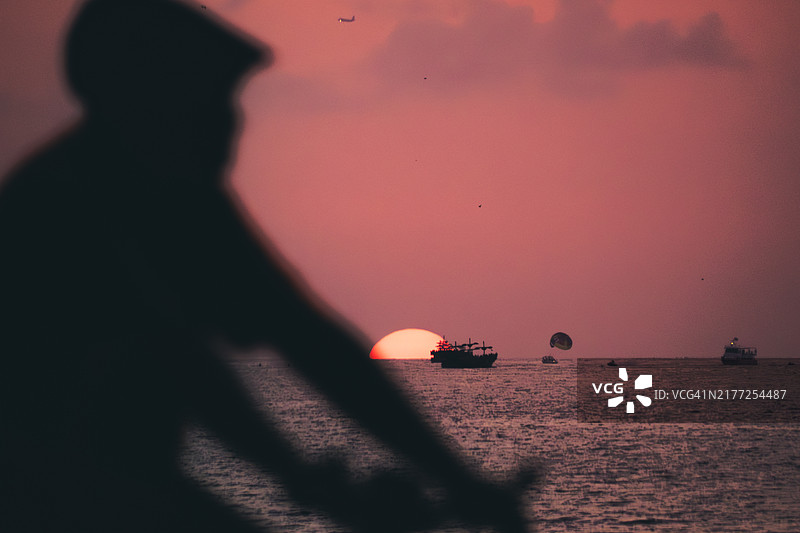 海面船只、滑翔伞与骑行者剪影日落图片素材