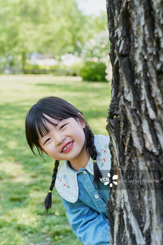 小女孩躲在木柱后大笑图片素材