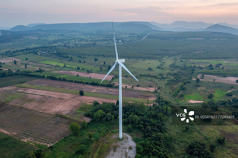 风力涡轮机在日落时分矗立在田野上，分散布置，利用可再生能源。图片素材