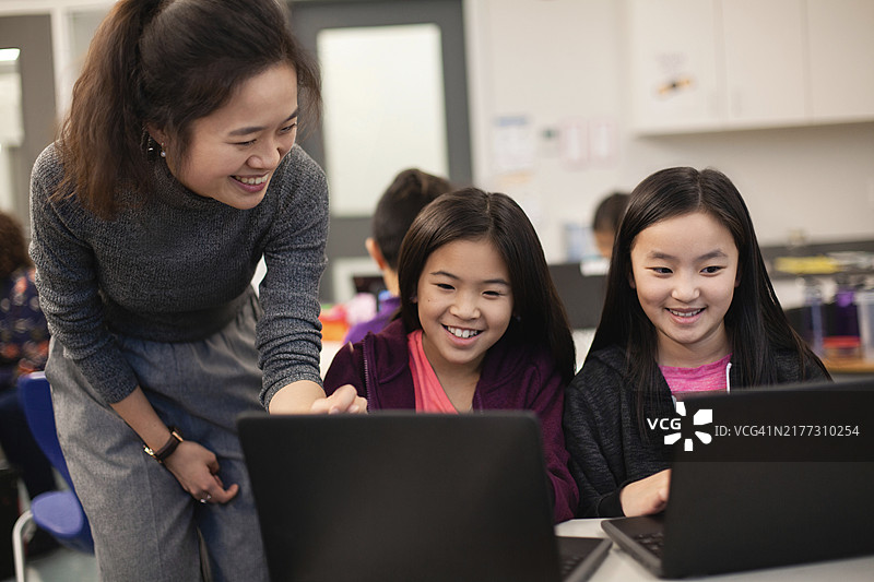 中年华人女教师指导学生使用电脑图片素材