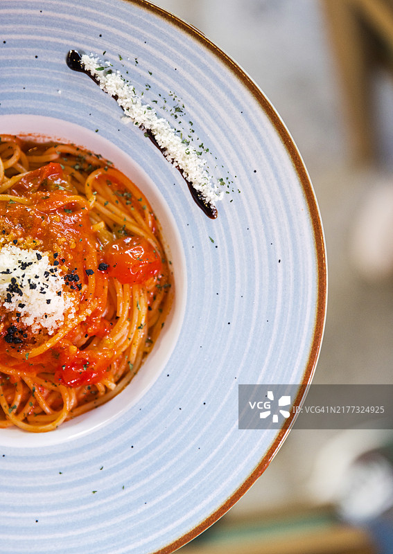优雅蓝色盘子里的美味番茄意面图片素材