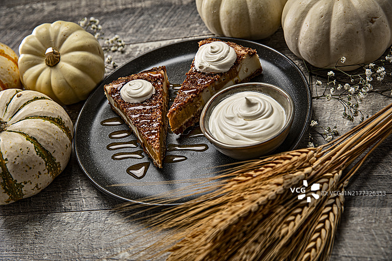 南瓜派芝士蛋糕和白色秋季南瓜与满天星鲜花，木质背景图片素材
