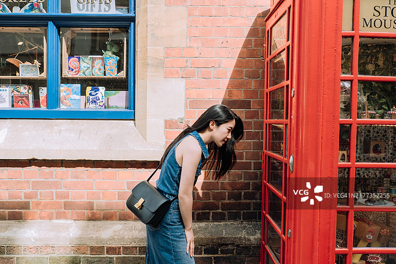 在伦敦街头电话亭看展览的亚洲女性图片素材