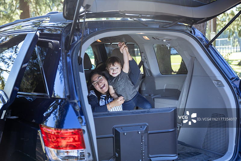 一家人坐在户外的SUV后面观看小电视屏幕图片素材