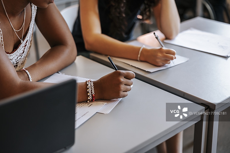 学生在教室课桌上写字的身体中部图片素材
