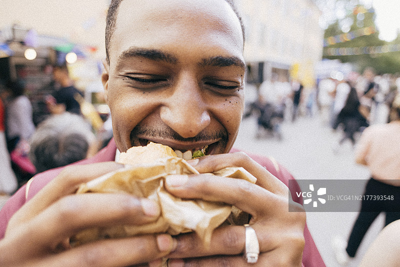 快乐的男人在美食节吃汉堡的特写镜头图片素材