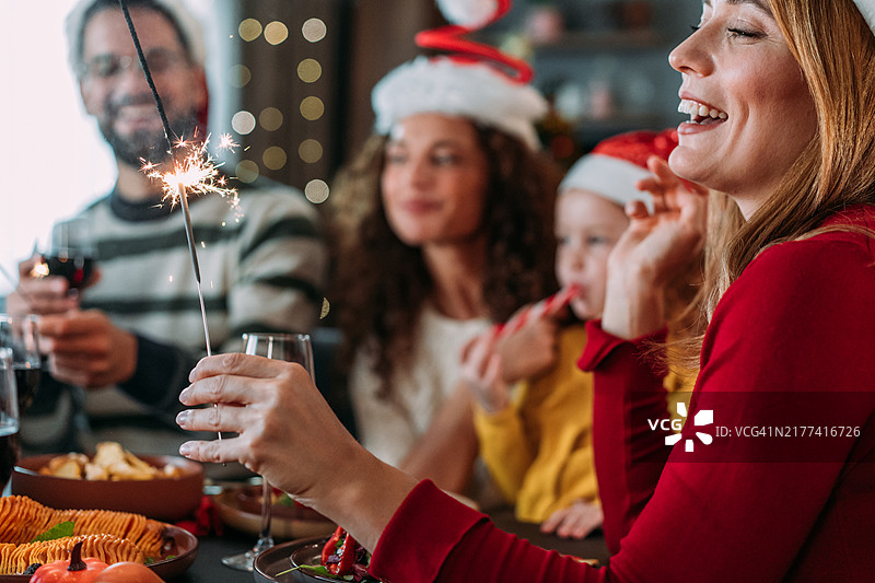 快乐的孩子和父母在圣诞前夜玩仙女棒图片素材