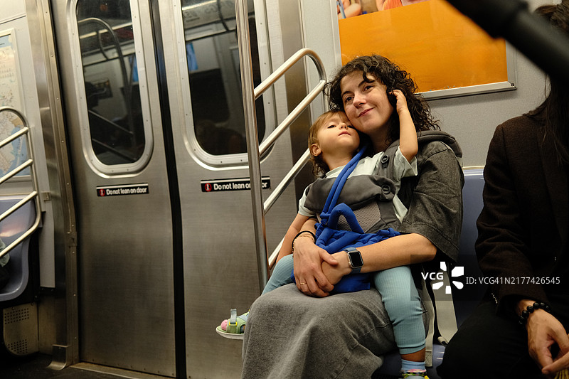 母亲乘坐地铁时抱着睡着的儿童图片素材