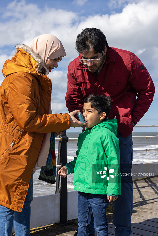 在父母的陪伴下使用吸入器的男孩图片素材