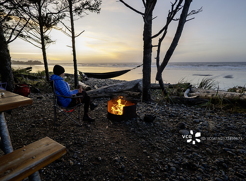 女人在篝火旁放松并眺望大海图片素材