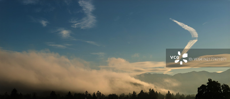 低角度日出山脉雾气弥漫的山谷，天空中的水汽轨迹图片素材